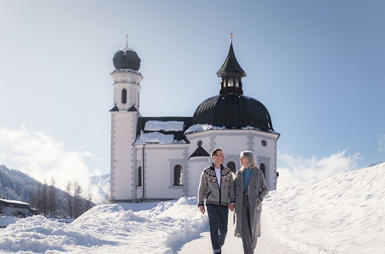 Paar auf Winter-Spaziergang durch Seefeld_Paar auf Weg vor Seekirchl