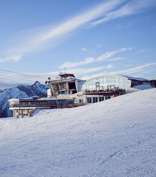 Schneebedeckte Berge mit einem modernen Gebäude im Vordergrund.