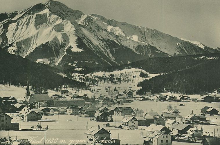 Schneebedecktes Dorf mit Bergen im Hintergrund in Winterlandschaft.
