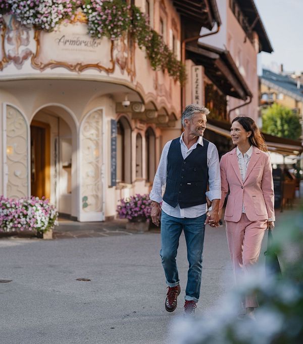 Paar spaziert durch malerische, blumengeschmückte Straße in der Region Seefeld.