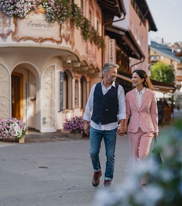 Paar spaziert durch malerische, blumengeschmückte Straße in der Region Seefeld.