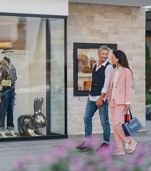Ein Paar geht neben einem Schaufenster mit modischer Kleidung spazieren.
