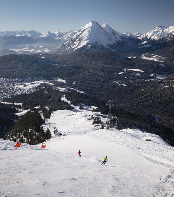 Skifahrer auf Piste in der Region Seefeld vor verschneiten Bergen.