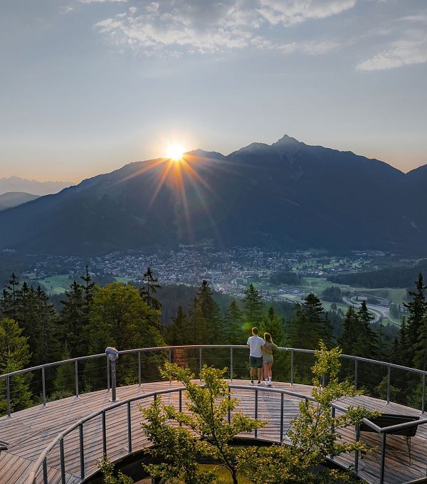 sonnenaufgang-aussichtsplattform-bruschkopf-drohnenaufnahme-paar-steht-am-gelaender-der-plattform-sonnenstern-ueber-seefelder-spitze-5
