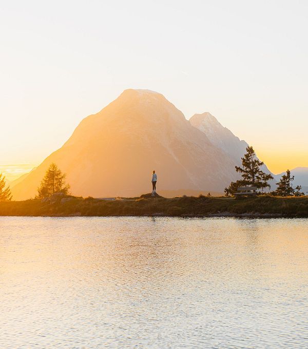 Person in der Region Seefeld vor Bergen bei Sonnenuntergang, ideal zum Wandern.