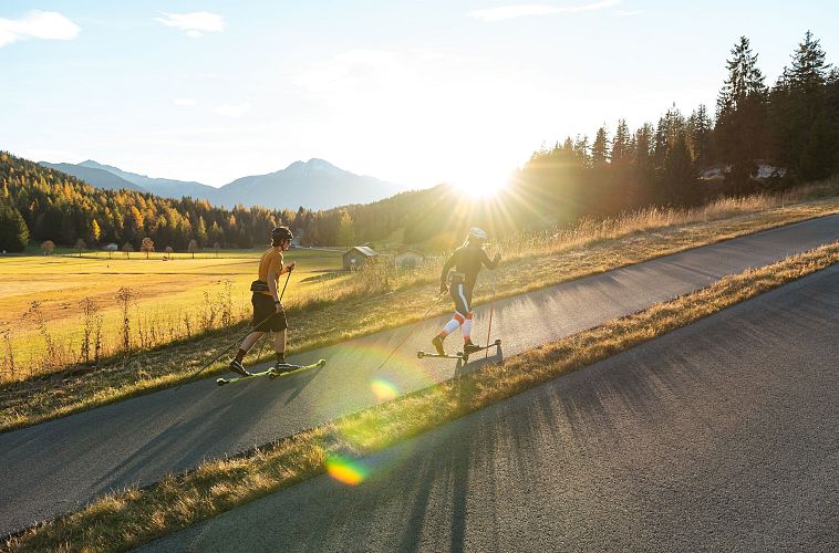 Sportler im Anstieg auf der Skirollerstrecke beim Sonnenuntergang im Herbst - Seefeld