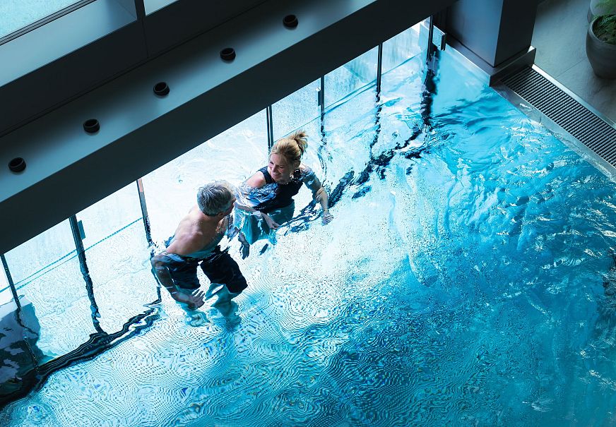 Alpenbad Leutasch im Frühling_Paar geht durch Tor im Pool