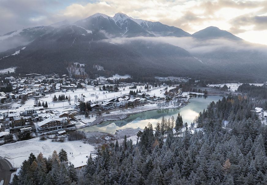 Winterlandschaft in der Region Seefeld mit Schnee, einem See und Bergen im Hintergrund.