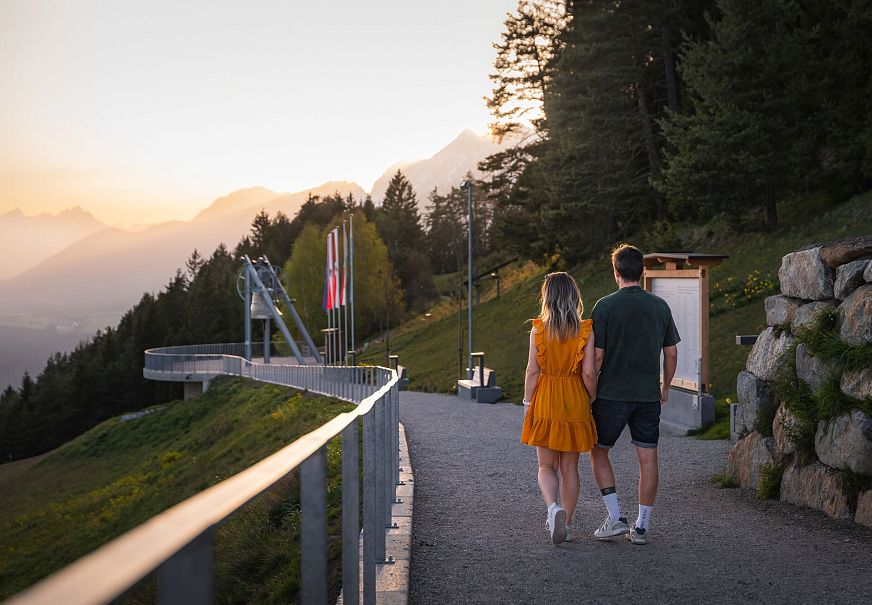Paar geht einen Weg in den Bergen bei Sonnenuntergang.