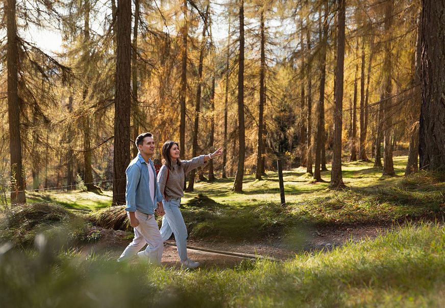sub1-herbstwanderung-im-laerchenwald-in-reith-paar-laeuft-durch-wald-frau-zeigt-auf-etwas-1