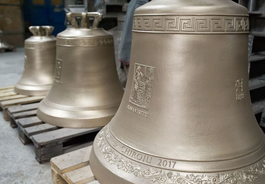 Several bronze bells with engravings arranged in a workshop.