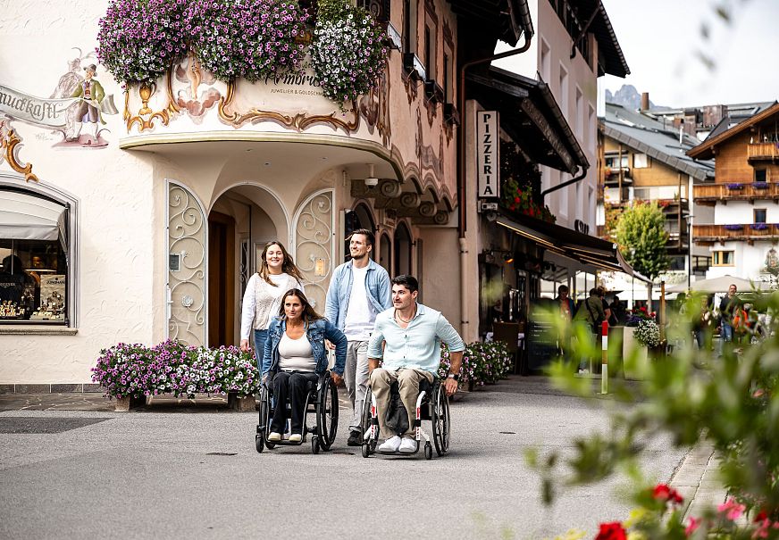 Gruppe mit Rollstühlen in malerischer Straße der Region Seefeld.
