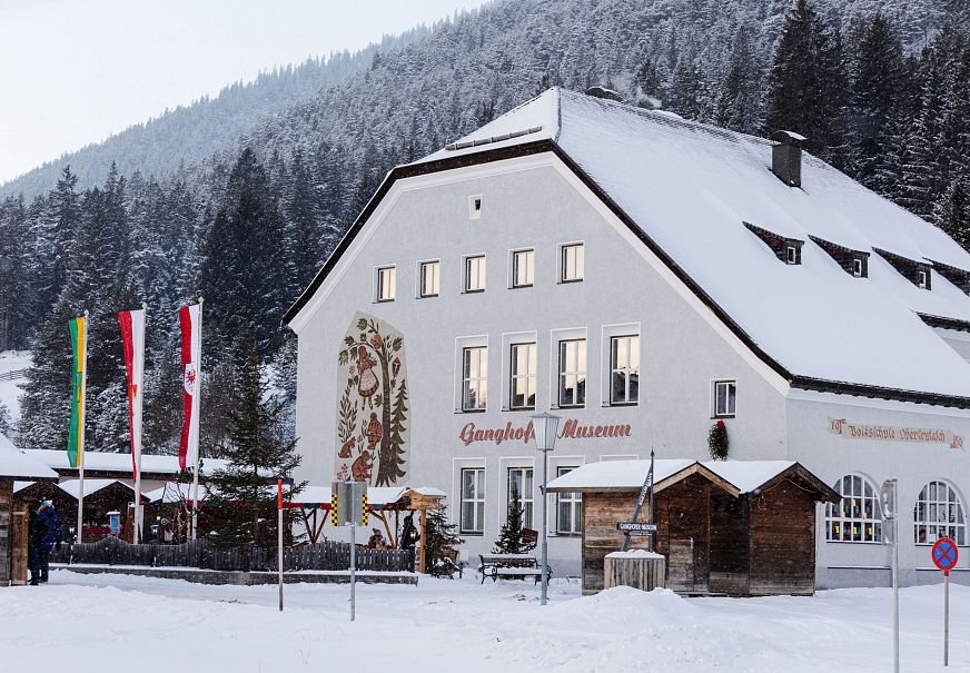 A snow-covered building with decorative elements and colorful flags in a winter landscape.