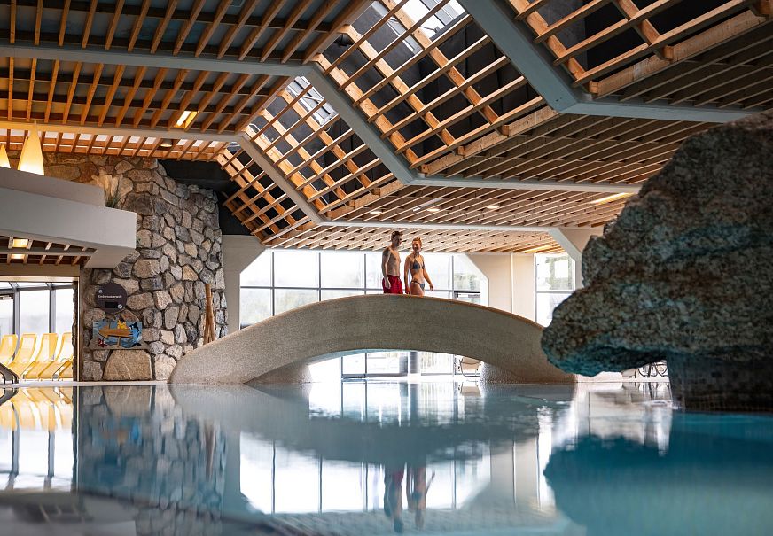 sub1-olympiabad-seefeld-paar-laeuft-ueber-bruecke-im-schwimmbadbereich