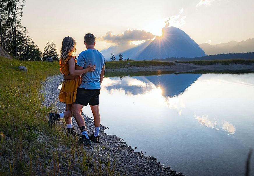Paar am Gschwandtkopf Speichersee blickt auf Hohe Munde bei Sonnenuntergang