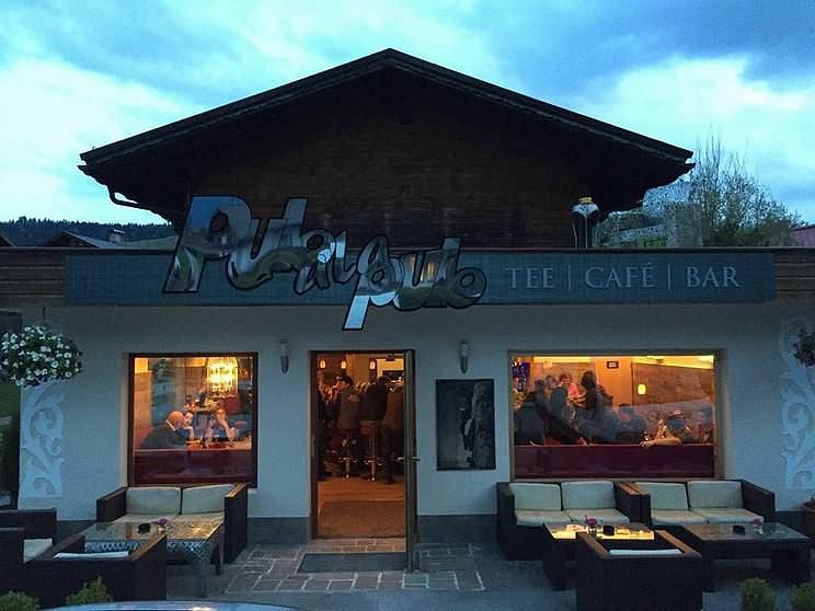 Fassade eines Cafés mit dem Schriftzug "Piano" und beleuchteten Fenstern.