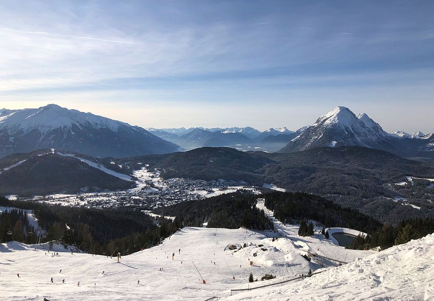 Winterlandschaft mit schneebedeckten Bergen und sonniger Piste.