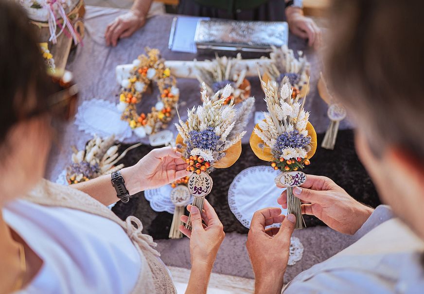 Due persone osservano bouquet di fiori essiccati su un tavolo di mercato.