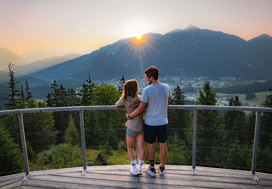 Sonnenaufgang Aussichtsplattform Bruschkopf - Paar steht am Geländer der Plattform - Aufnahme von hinten - Paar schaut sich an