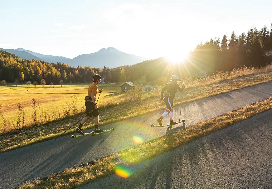 sportler-im-anstieg-auf-der-skirollerstrecke-beim-sonnenuntergang-im-herbst-seefeld