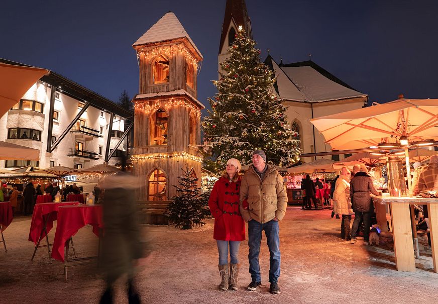Weihnachtsmarkt Seefeld_Langzeitaufnahme_Paar steht vor Glockenturm_Aufnahme von vorne