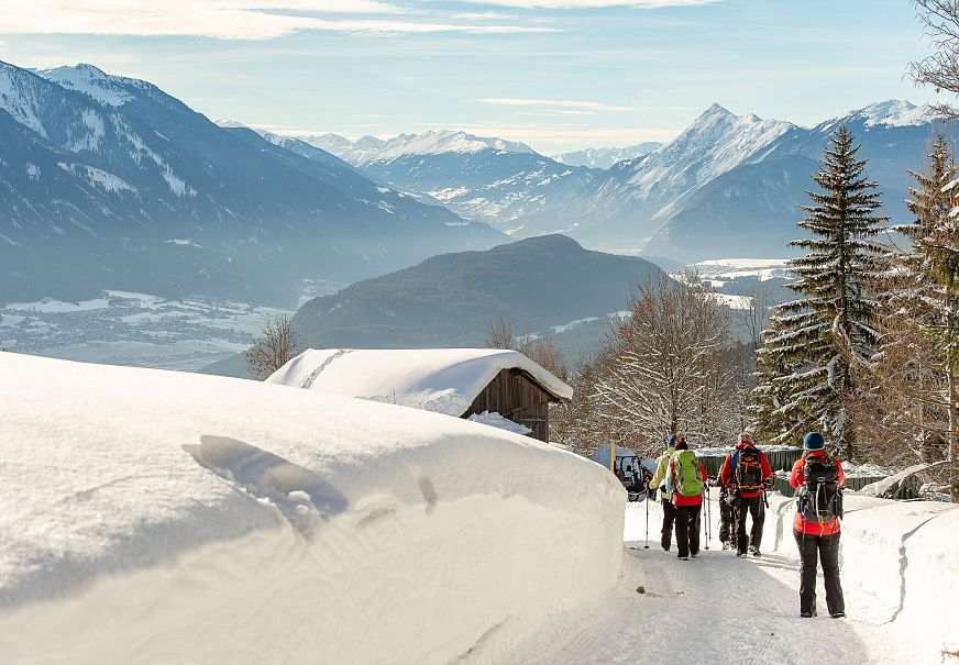 Verschneiter Bergpfad mit Wanderern in der Region Seefeld, umgeben von Alpen.