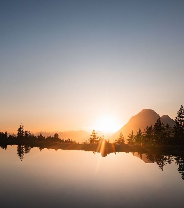 Untergehende Sonne neben der Hohen Munde mit Kaltwassersee im Vordergrund