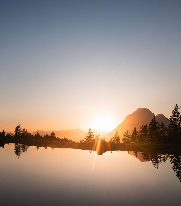 Untergehende Sonne neben der Hohen Munde mit Kaltwassersee im Vordergrund