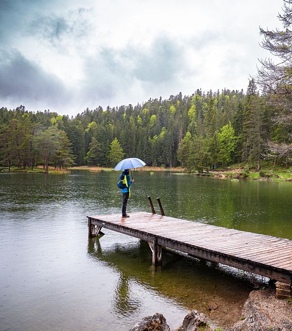 Wanderer steht auf dem Steg des Möserer Sees