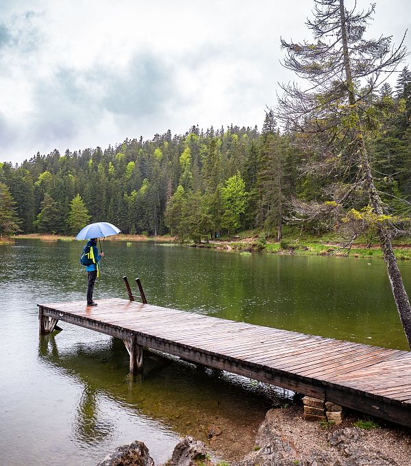 Wanderer steht auf dem Steg des Möserer Sees