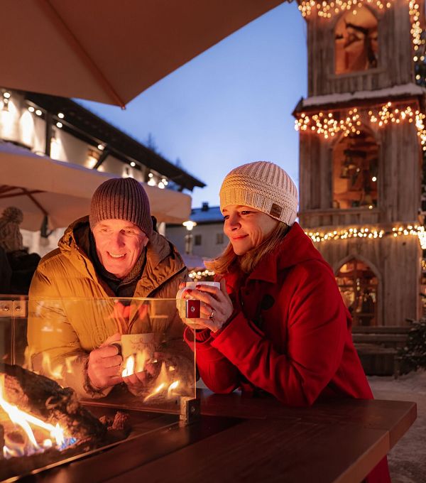 weihnachtsmarkt-seefeld-paar-steht-am-feuertisch-mann-und-frau-schauen-ins-feuer-1