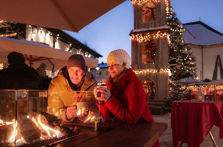weihnachtsmarkt-seefeld-paar-steht-am-feuertisch-mann-und-frau-schauen-ins-feuer