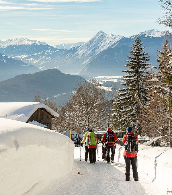 Verschneiter Bergpfad mit Wanderern in der Region Seefeld, umgeben von Alpen.