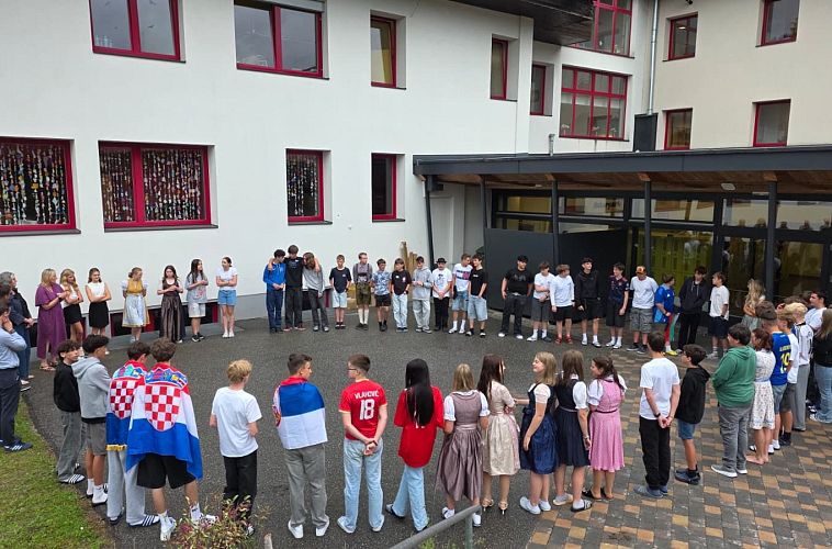 Schüler versammeln sich zu einer Veranstaltung in einem Innenhof vor einem Schulgebäude.