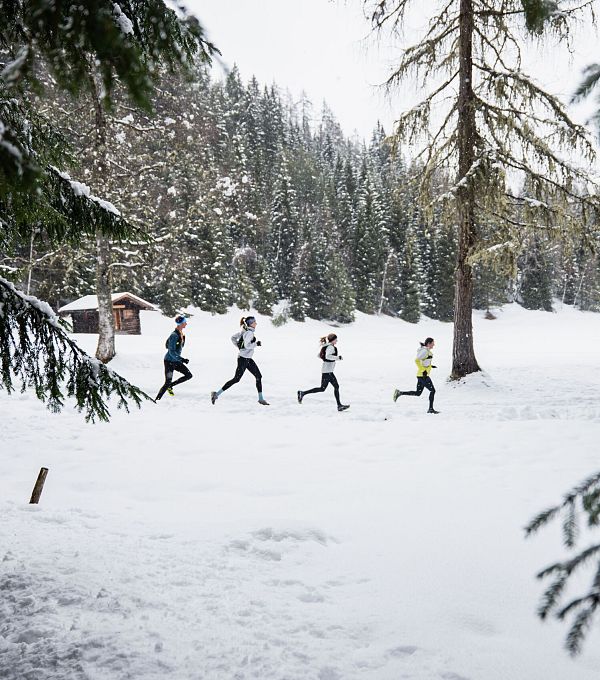 wintertrailrunning-in-der-region-seefeld-laeufer-in-einer-reihe-mit-holzhuette-im-hintergrund-1