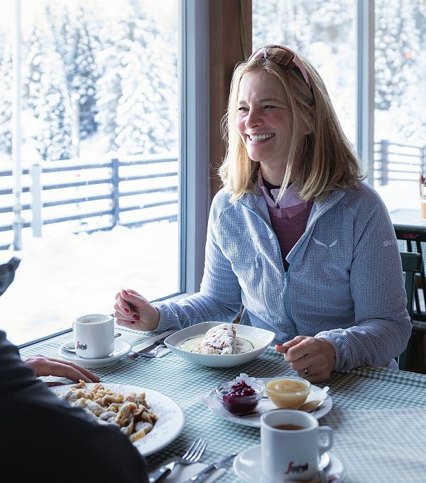 Una donna e un uomo stanno facendo colazione in un caffè con vista sulla neve.