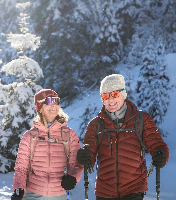 Zwei Personen beim Winterwandern in einer schneebedeckten Landschaft.