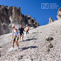 Wanderer auf steinigem Gebirgspfad mit blauen Himmel und Felsen.