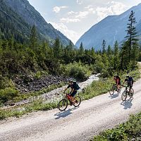 Mountainbiker in den Bergen der Region Seefeld auf einer Schotterstraße, umgeben von Wald und Gebirge.