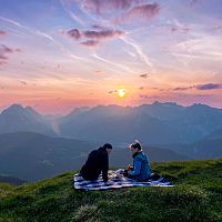 Ein Paar sitzt beim Sundowner Picknick mit Blick Richtung Leutasch