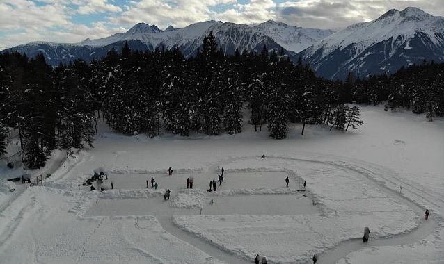 Verschneite Landschaft in der Region Seefeld mit Menschen beim Eislaufen und umliegenden Bergen.