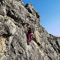 Eine Person klettert an einer felsigen Wand mit Sicherheitsausrüstung.