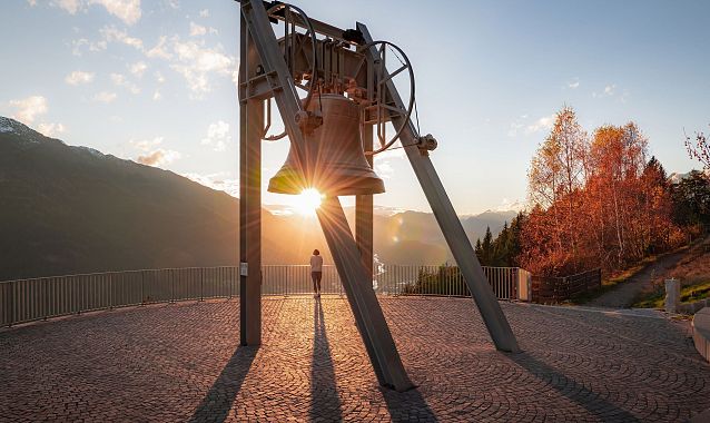 Friedensglocke im Herbst - Frau blickt ins Inntal beim Sonnenuntergang - Sonnenstern an der Glocke