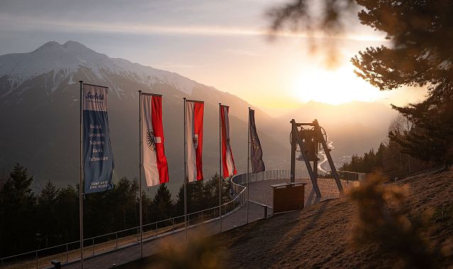 Friedensglocke Mösern - Sonnenuntergang mit Zweigen im Vordergrund