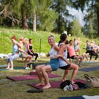 Eine Gruppe von Frauen macht Yoga-Übungen im Freien auf einer Wiese.