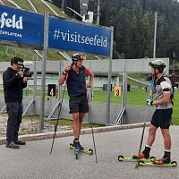 Zwei Männer mit Helmen und Skistöcken im Sommer bei Rollski-Training, Region Seefeld; ein Kameramann filmt sie.