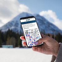 Person hält Smartphone mit Karte der Region Seefeld, schneebedeckter Berg im Hintergrund.