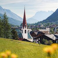 Pfarrhügel Seefeld im Sommer_Blick auf Pfarrkirche mit Blumen im Vordergrund_Hochformat