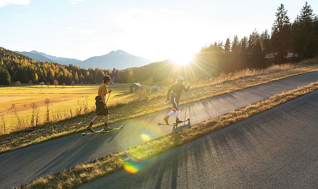 Sportler im Anstieg auf der Skirollerstrecke beim Sonnenuntergang im Herbst - Seefeld