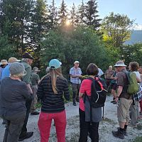 Eine Gruppe von Menschen bei einem Vortrag auf einem Wanderweg in der Natur.